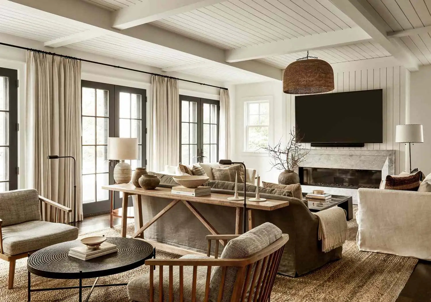 Beige upholstered sectional sofa with wooden legs and a textured throw blanket draped over one arm.