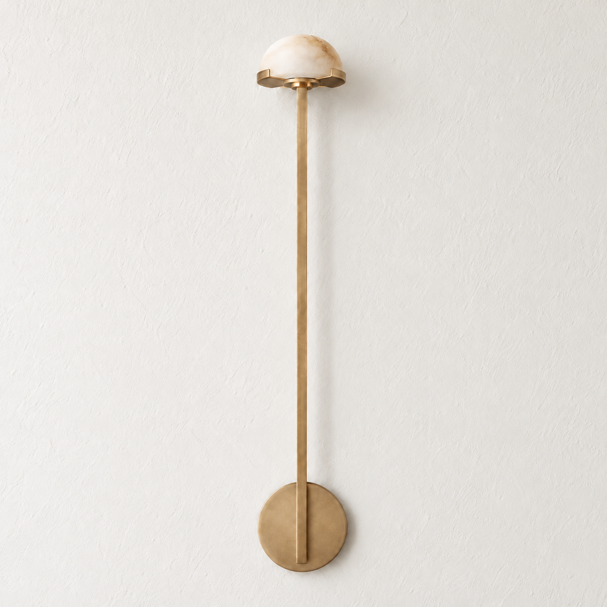Tall brass wall sconce with a small alabaster dome, switched off on ivory plaster.