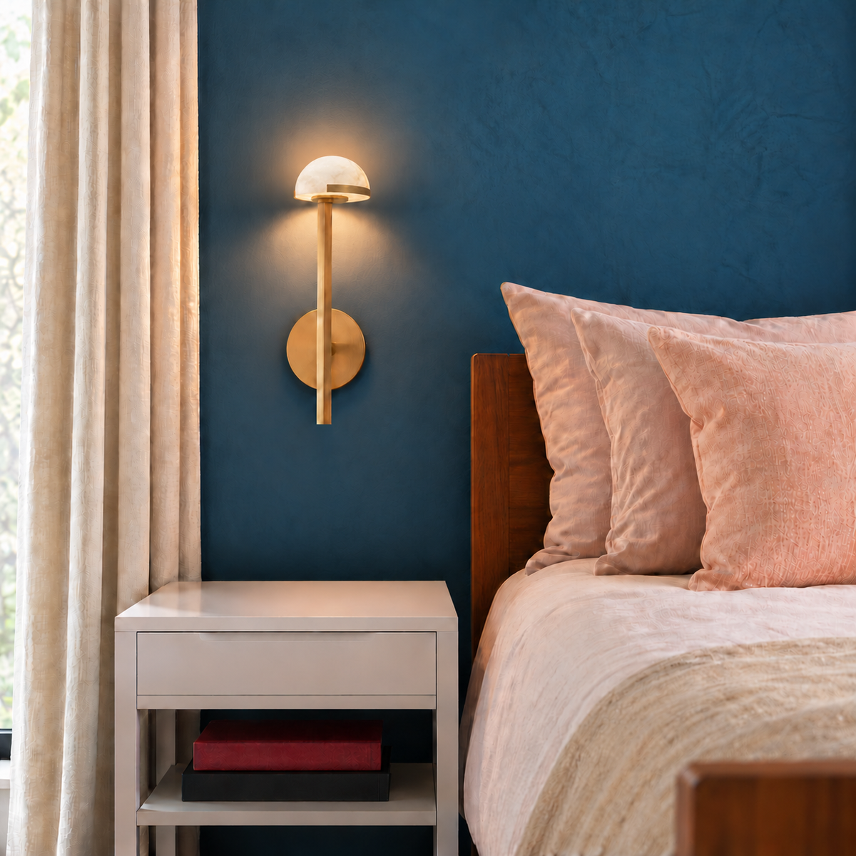 Compact brass and alabaster wall sconce beside a bed in a blue bedroom.