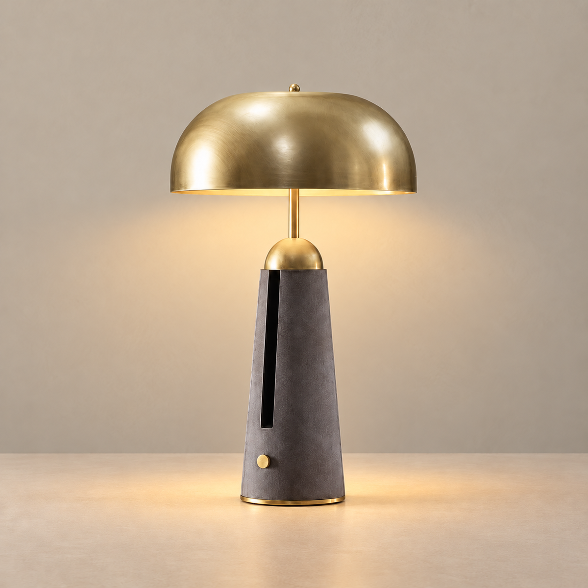 Brass dome table lamp with a charcoal leather base, illuminated on a beige background