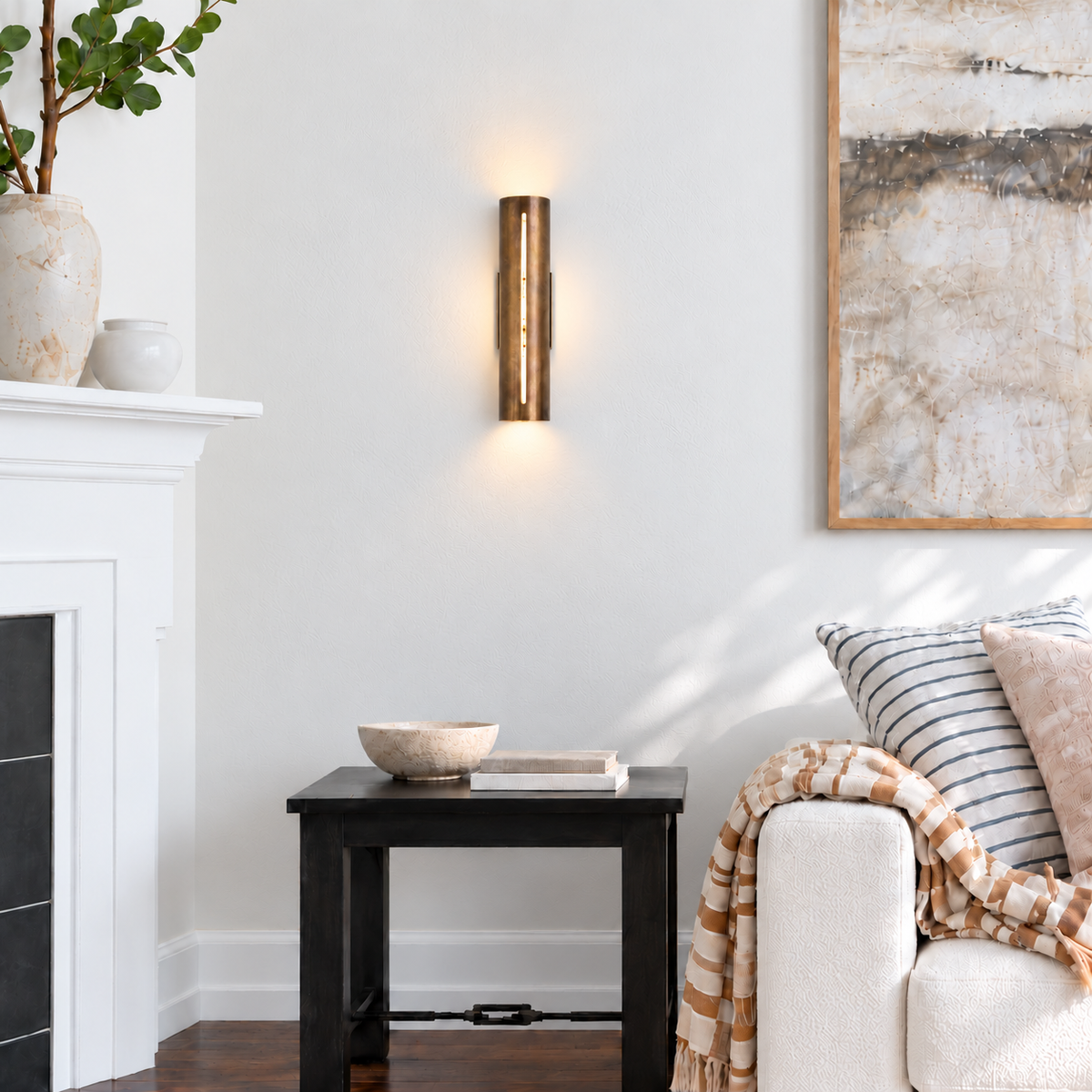 Copper cylinder wall light installed on an ivory living-room wall beside a chair and fireplace.