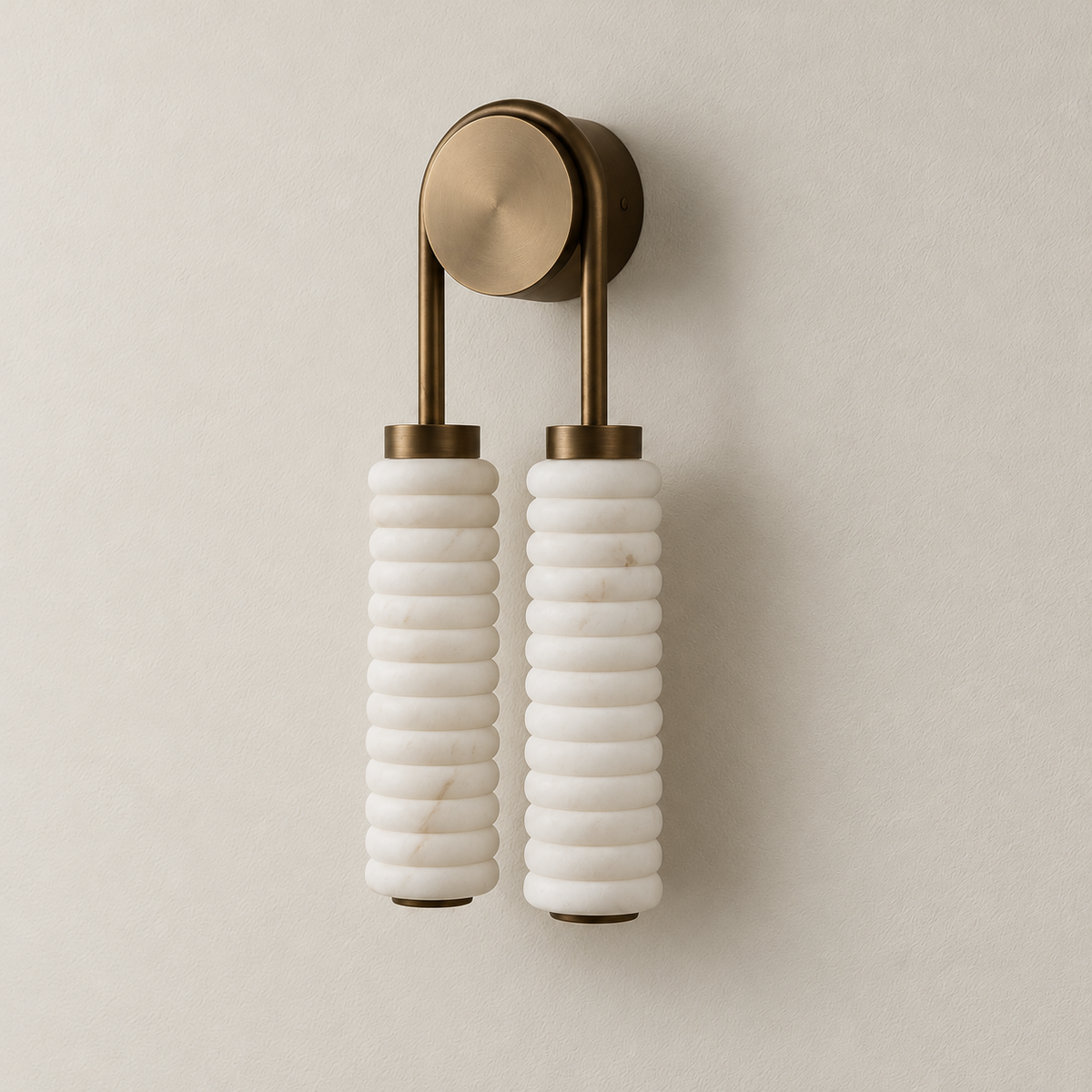 Angled view of the double marble sconce showing its round brass backplate and twin ribbed cylinders.