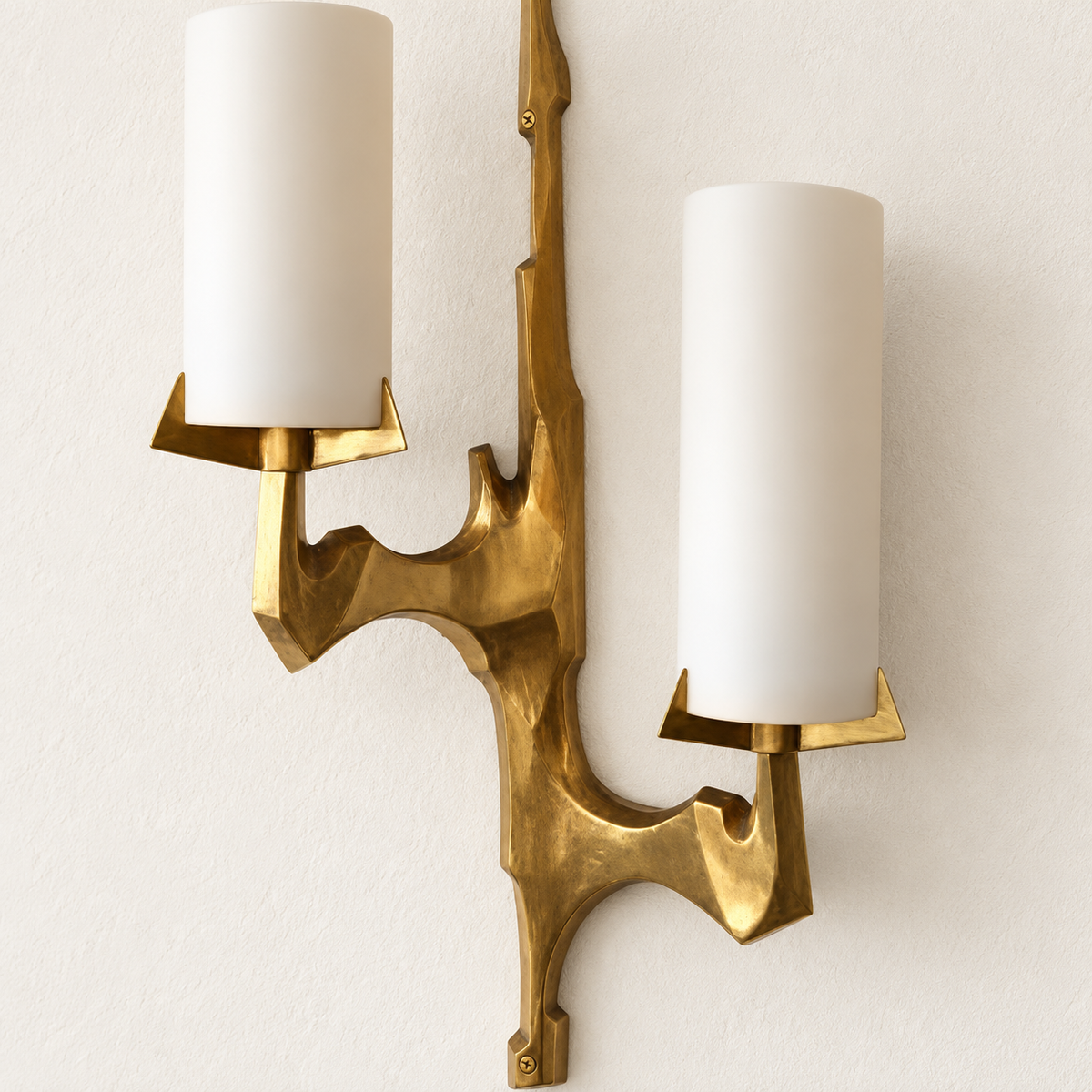 Angled view of sculptural brass sconce with two staggered opal glass shades, showing its construction.