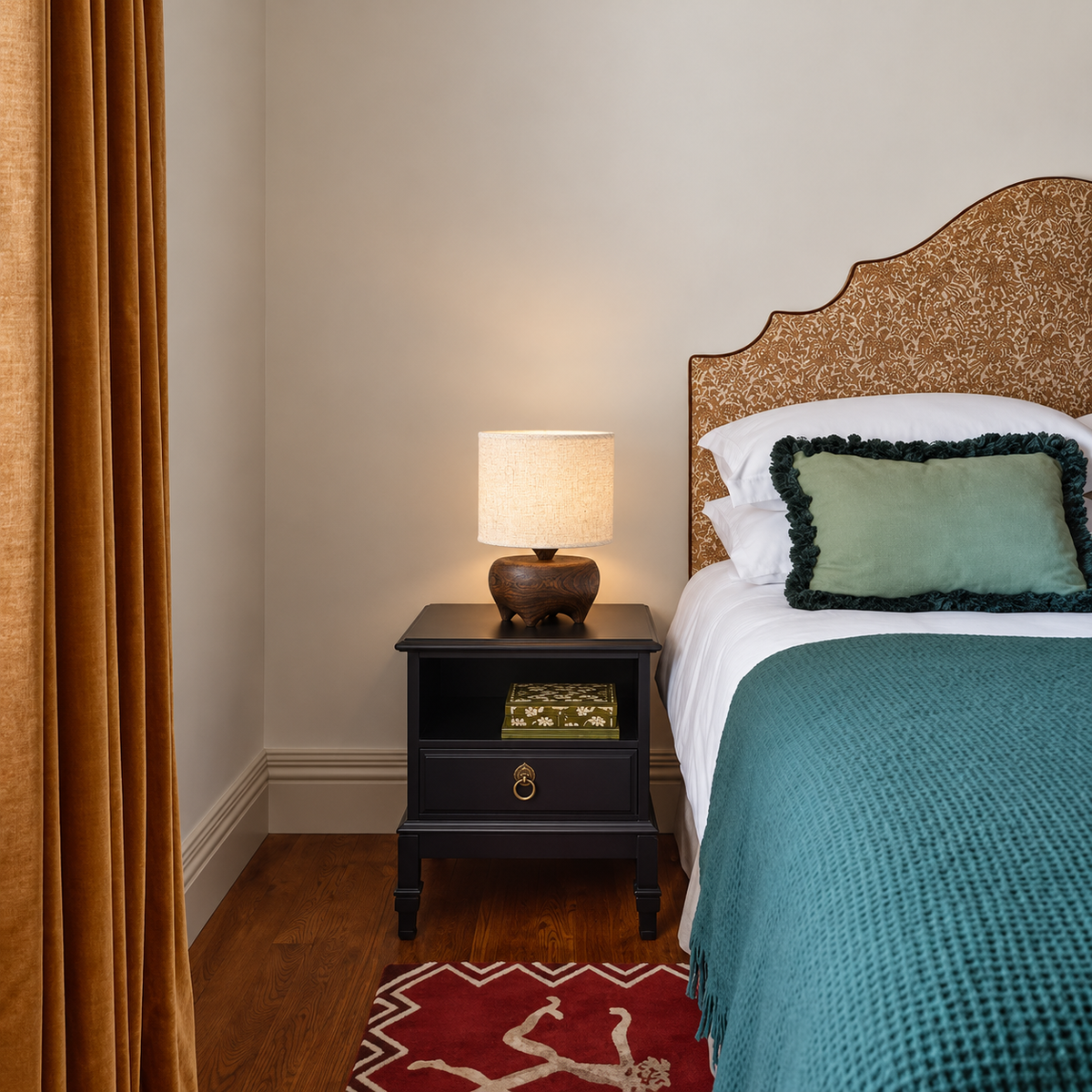 Small carved wood table lamp on a bedside table beside teal bedding