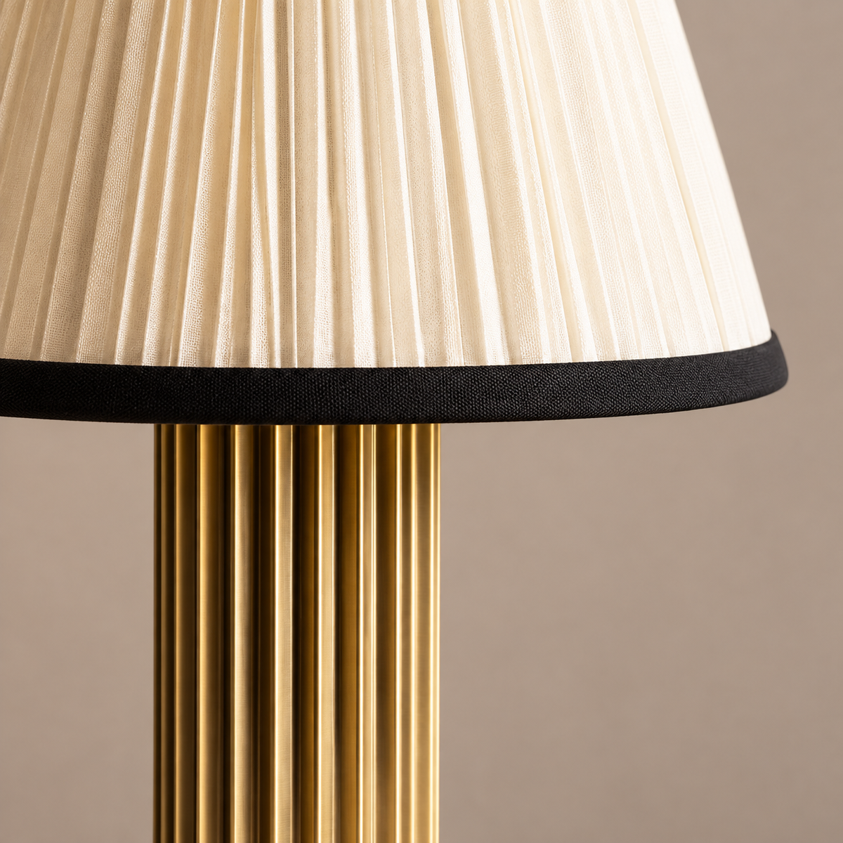 Close view of the pleated fabric shade, black trim and fluted brass column