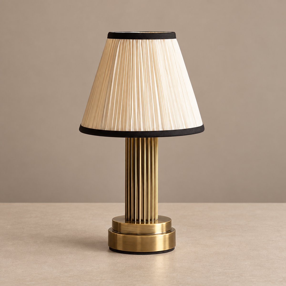 Fluted brass table lamp with black-trimmed pleated fabric shade, unlit