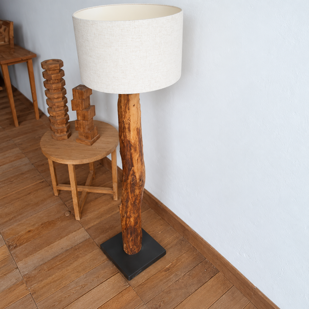 Legno Rustico floor lamp on a timber floor beside a round wooden table and carved sculptures.