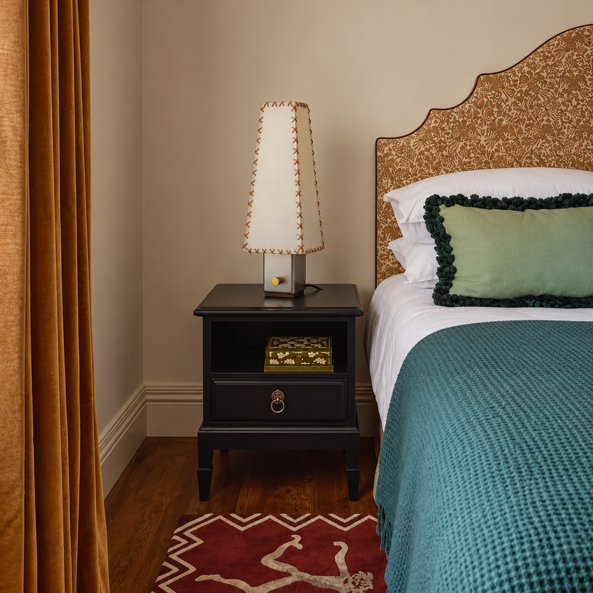 Stitched parchment lamp beside a teal-covered bed.