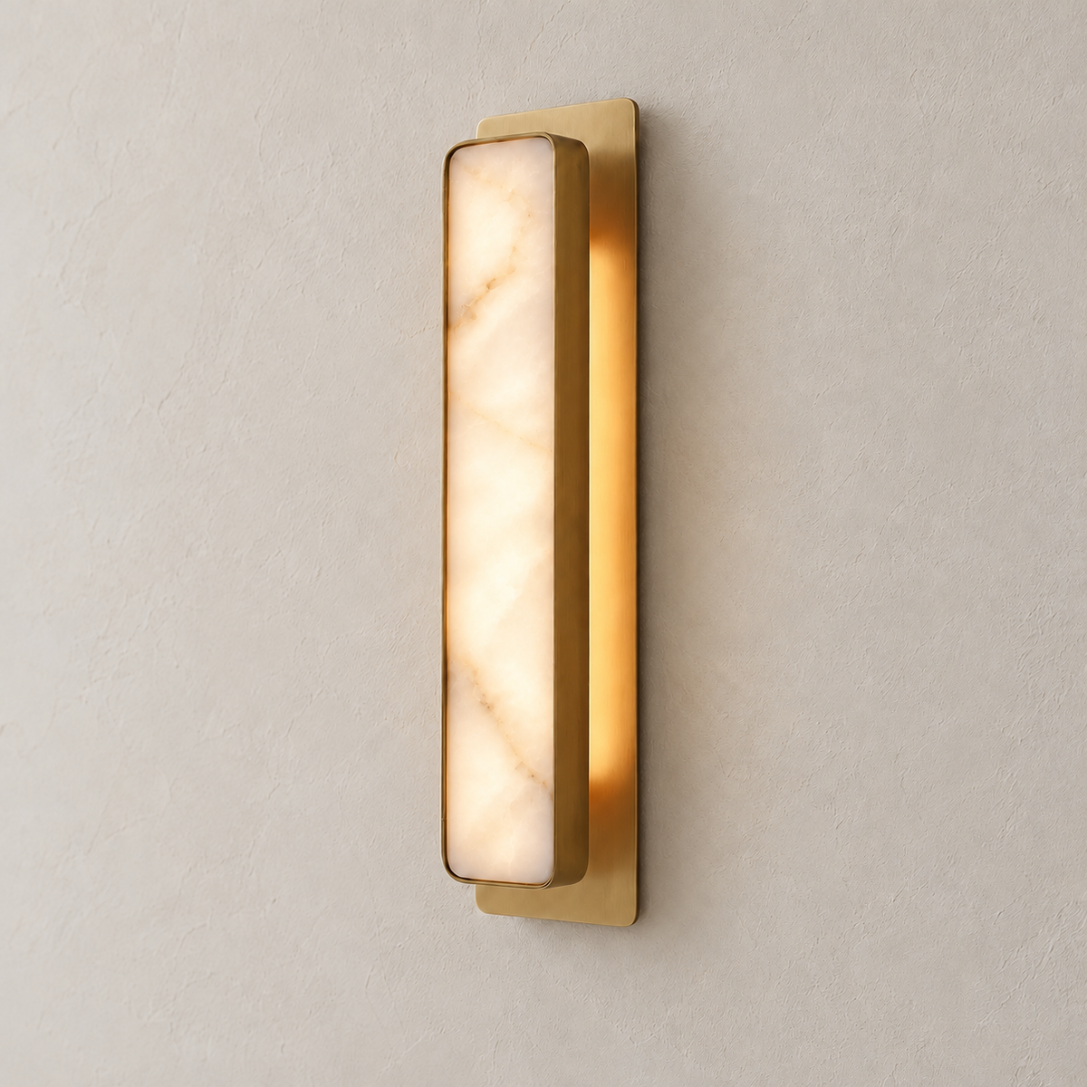 Angled view of the Mont alabaster light and its rectangular brass backplate.