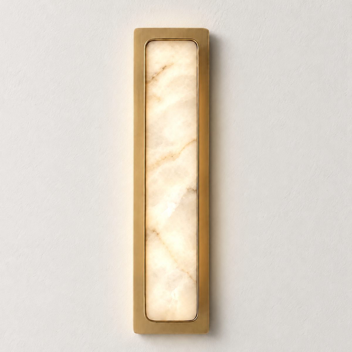 Mont alabaster and brass wall light, illuminated on ivory plaster.