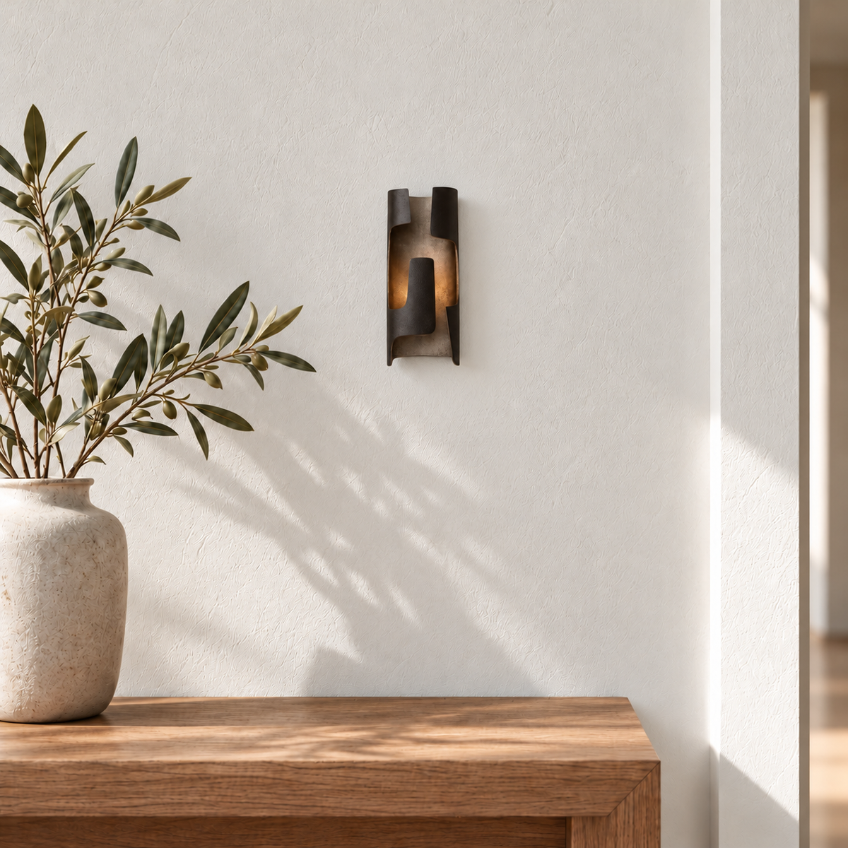 Slender dark patinated bronze folded sconce mounted in a daylight entryway.