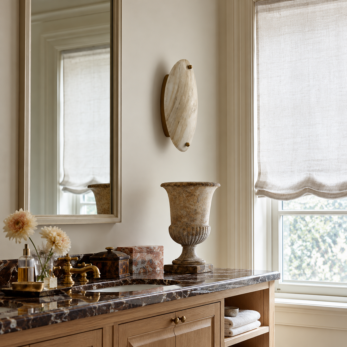Oval marble wall sconce beside a vanity mirror in a bathroom with timber cabinetry.