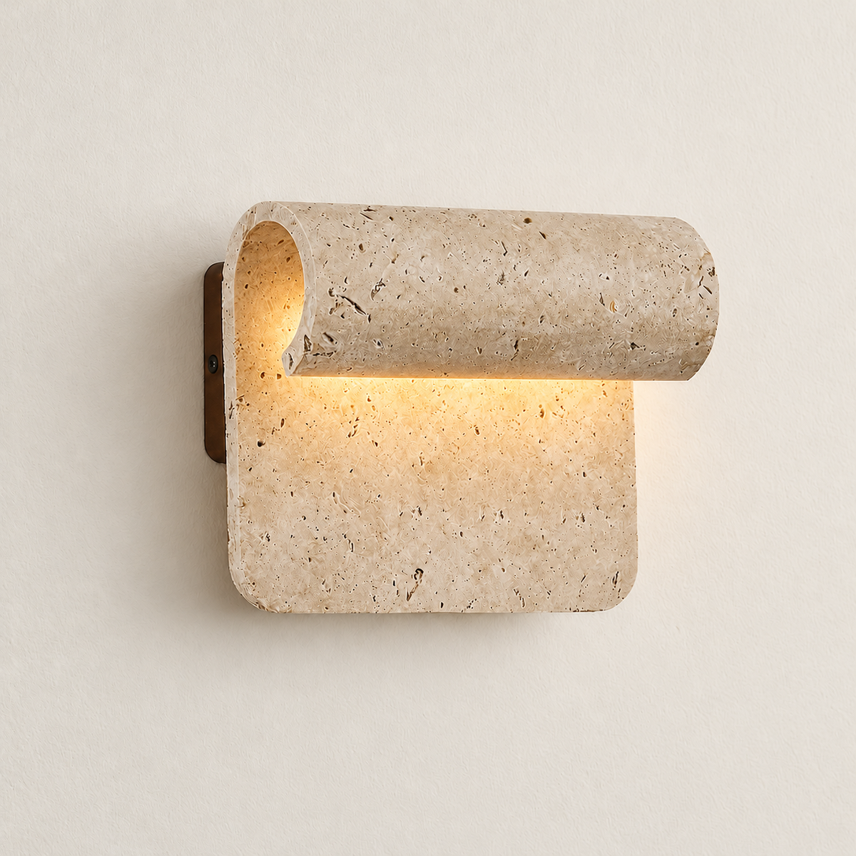 Curved travertine wall sconce with a rolled upper edge illuminated against the same ivory backdrop.