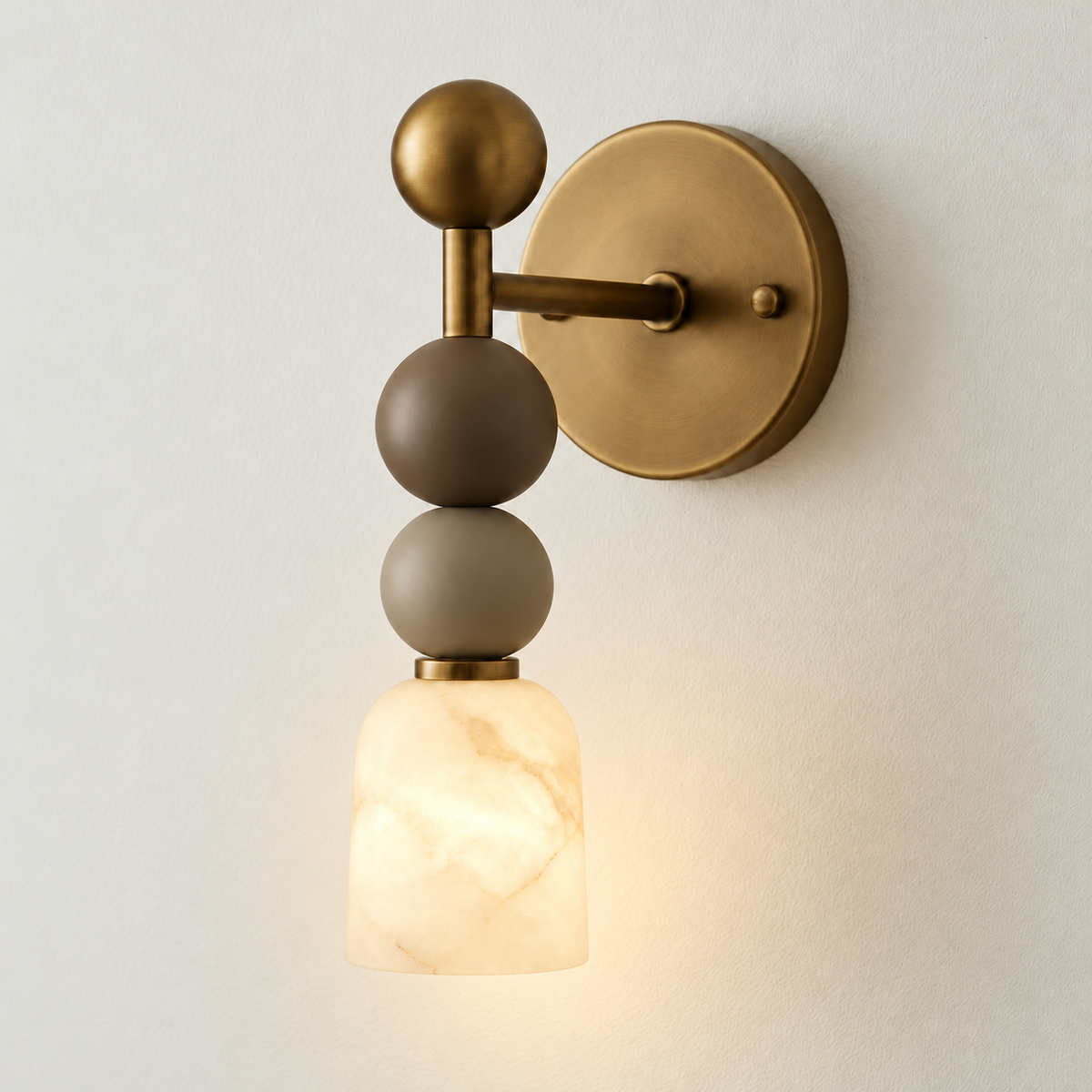 Alabaster and brass wall sconce with stacked spheres illuminated in the matching ivory composition.