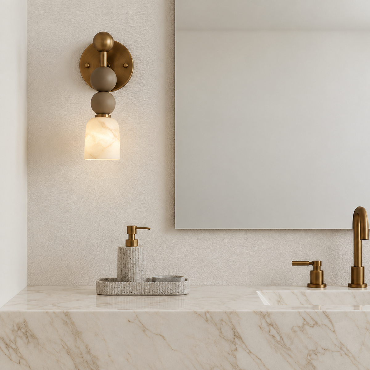 Alabaster and brass wall sconce with stacked spheres mounted beside a vanity mirror in natural daylight.