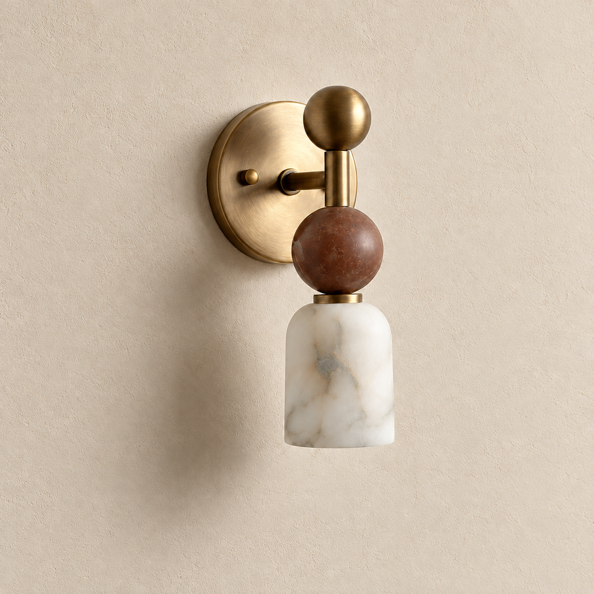 Angled view of the unlit Totem Petite brass wall sconce, showing its projecting arm, marble sphere and veined alabaster shade.
