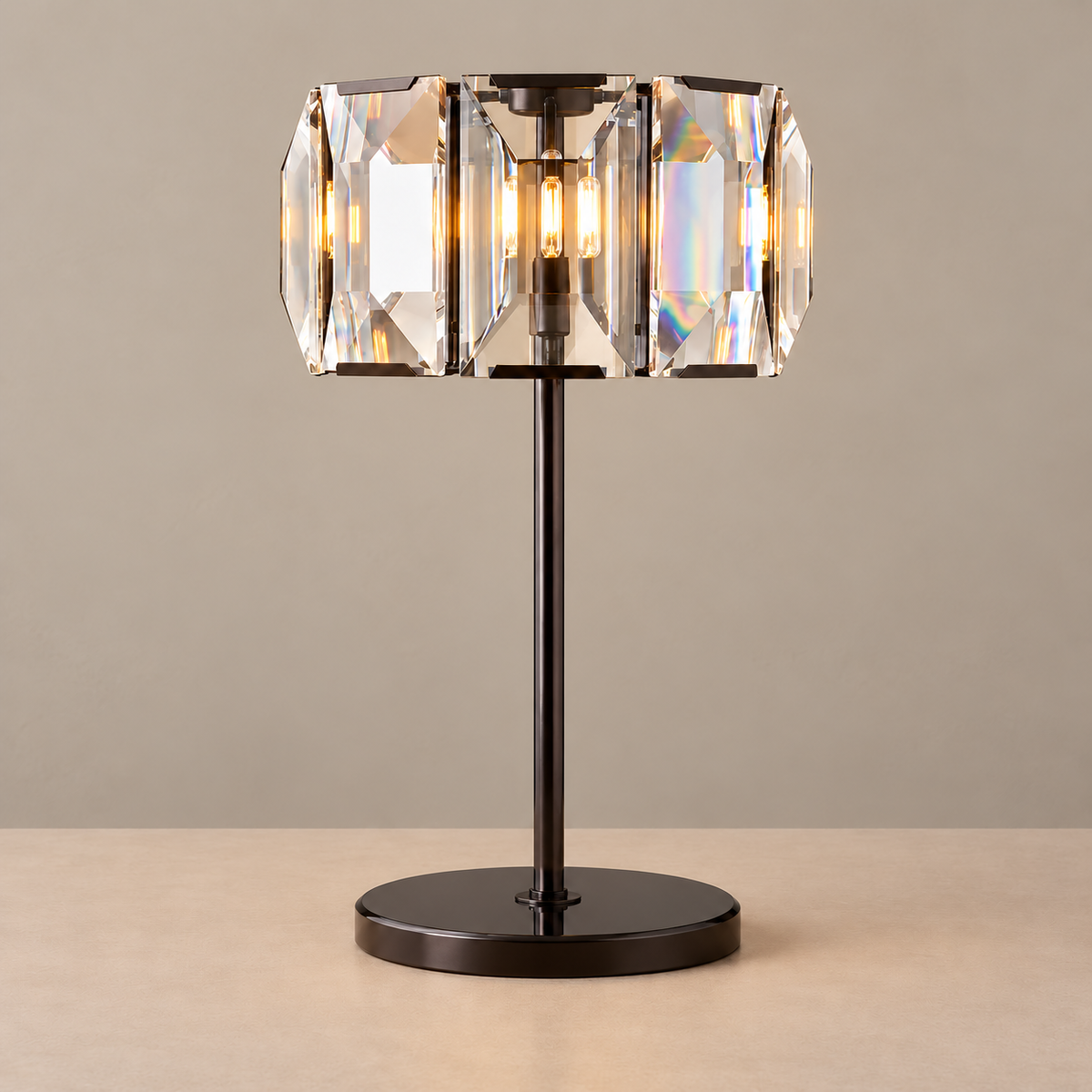 Crystal drum table lamp with a dark metal stem and round base, illuminated on a beige background