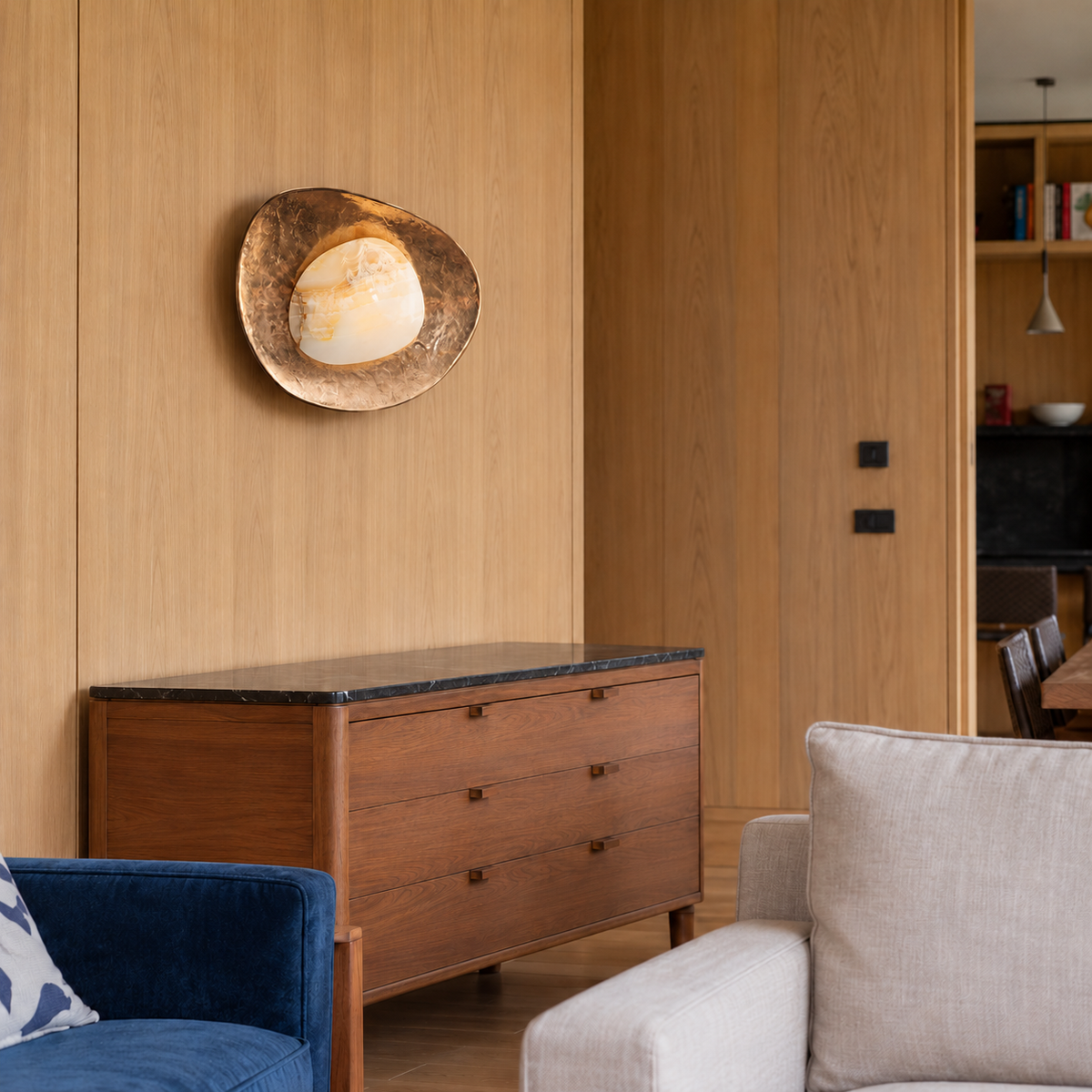 Marble and brass wall sconce above a wooden cabinet in a timber-panelled living room.