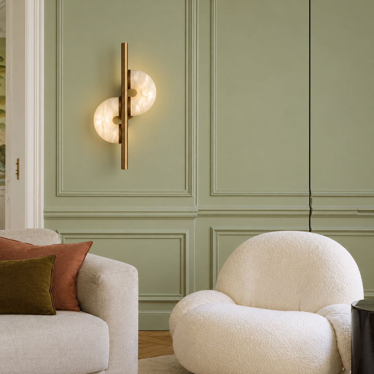 Alabaster and bronze sconce installed in a sage green living room.