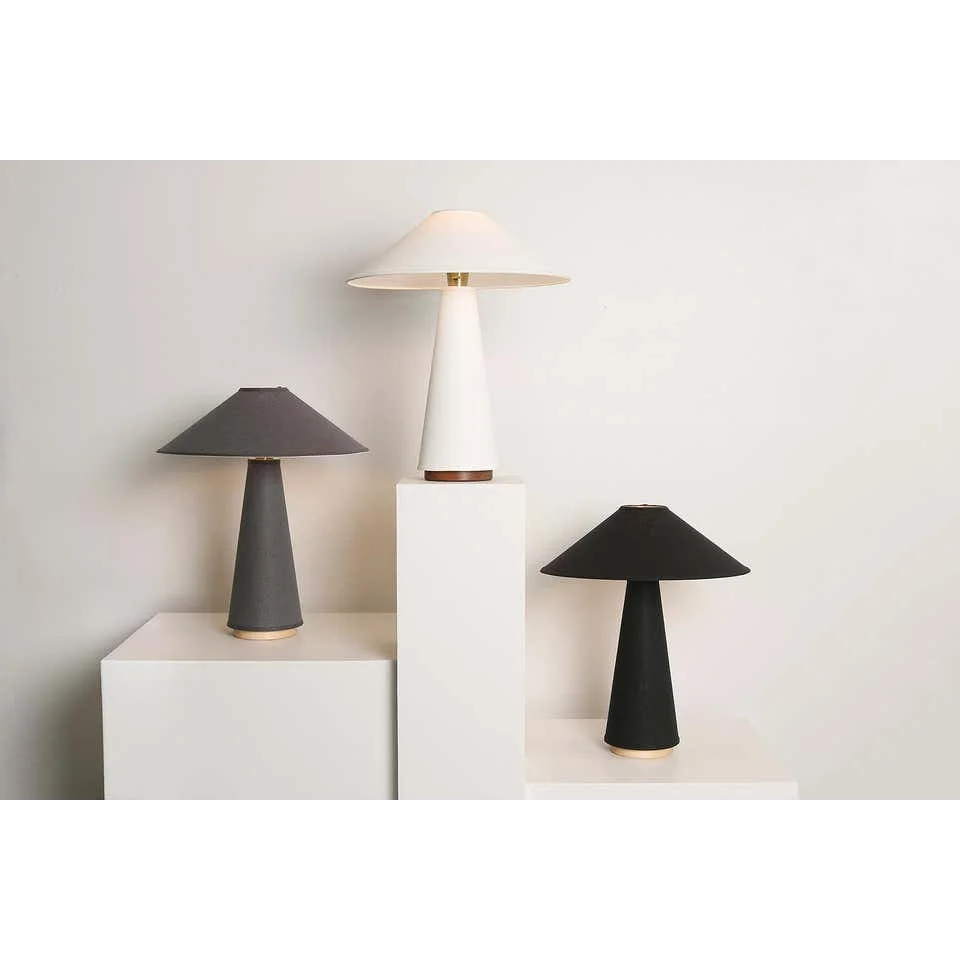 Table lamp with a hand-knitted textile shade beside a bed