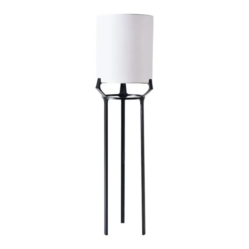 Slim stainless-steel floor lamp with a white fabric shade in a living room