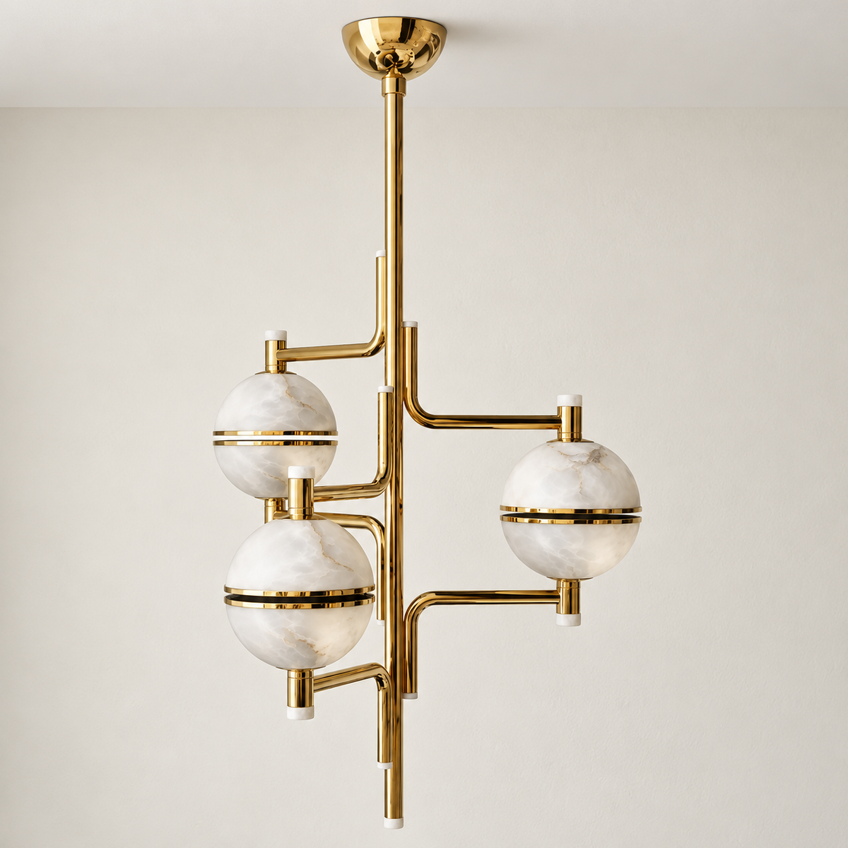 Unlit Orbital chandelier with three alabaster globes on an asymmetric brass frame.