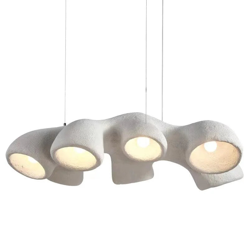 Organic sculptural ceramic-composite pendant with downlight apertures over a kitchen island