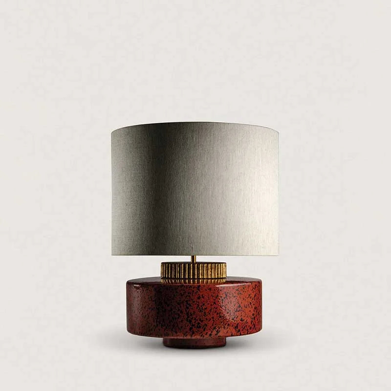 Red ceramic table lamp with metallic drum shade on a console