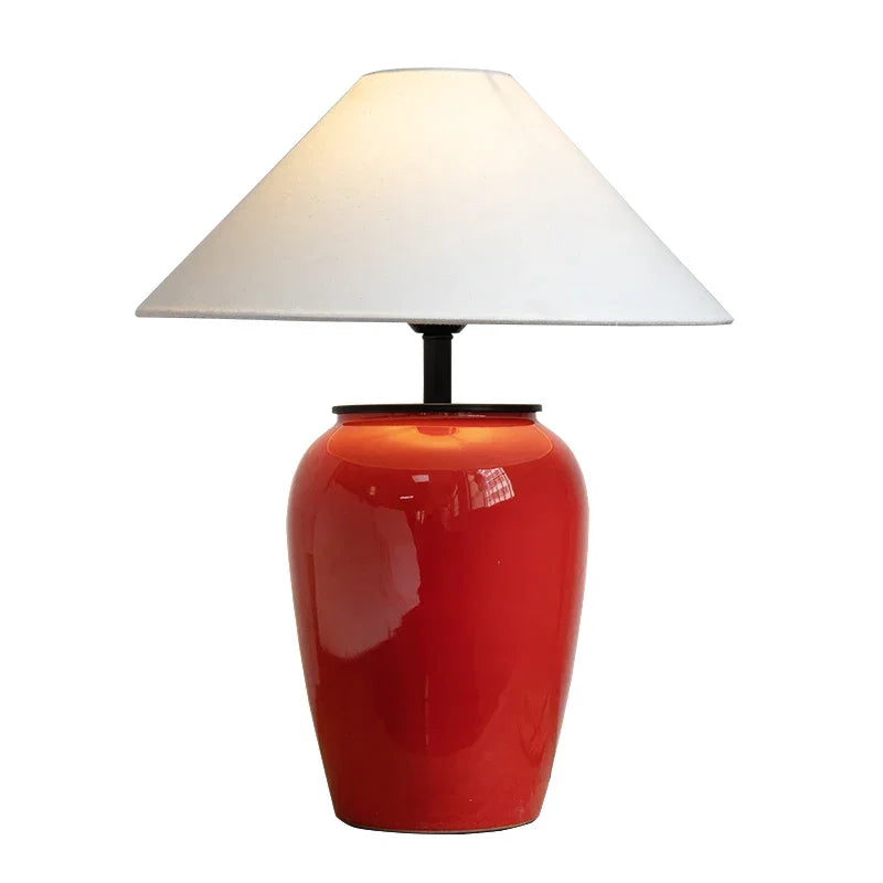 Bold red ceramic table lamp with a fabric shade on a sideboard
