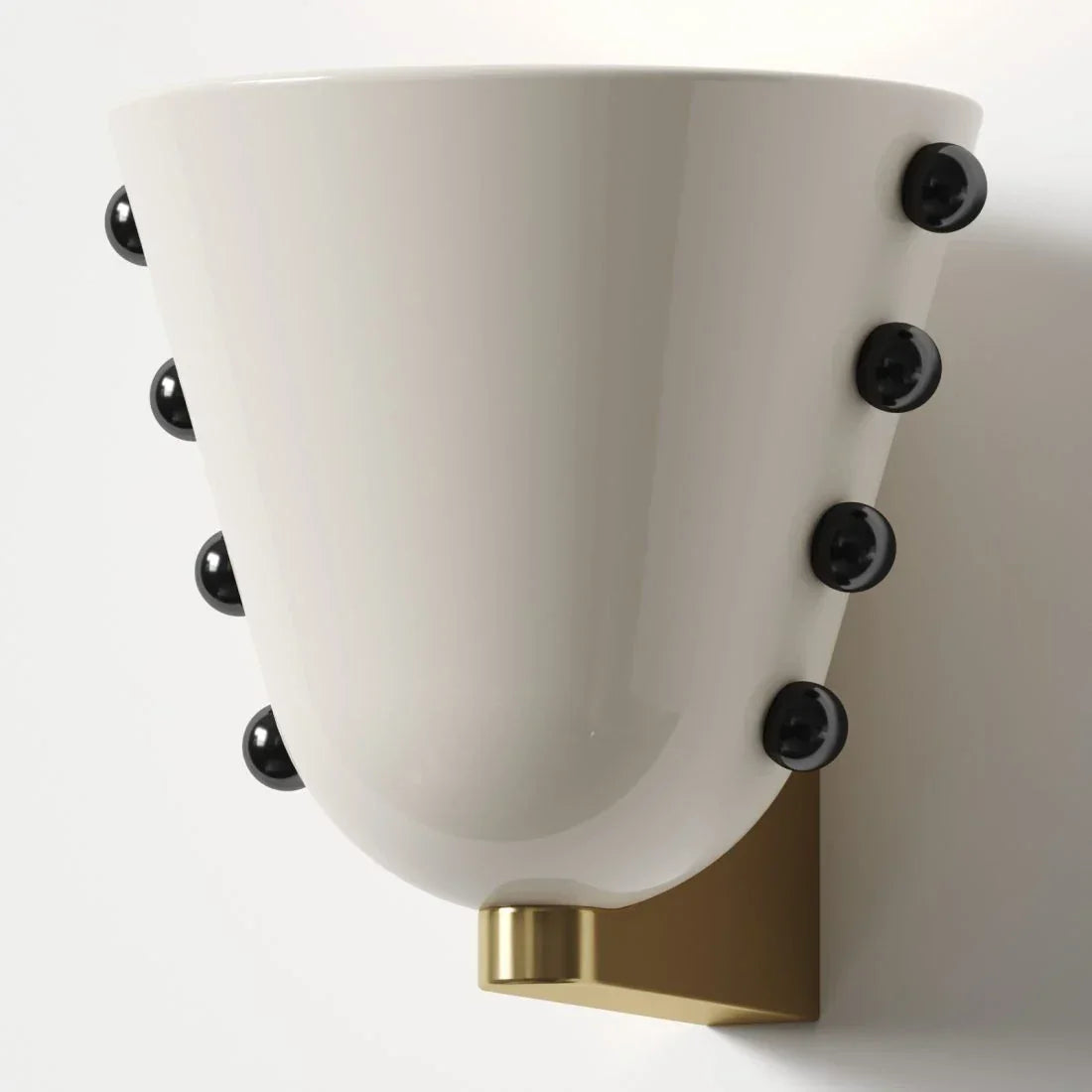 White cone wall sconce with black studs and brass mount framing a vanity