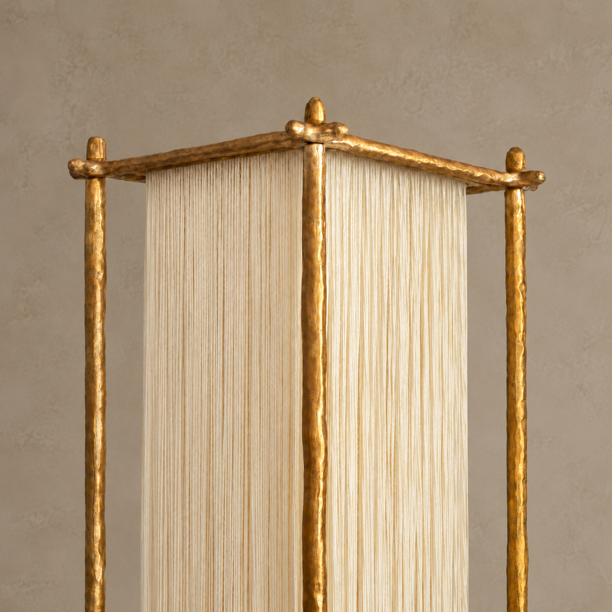 Close view of Cascade's hammered gold-tone top rails and the ivory silk strands suspended beneath them.