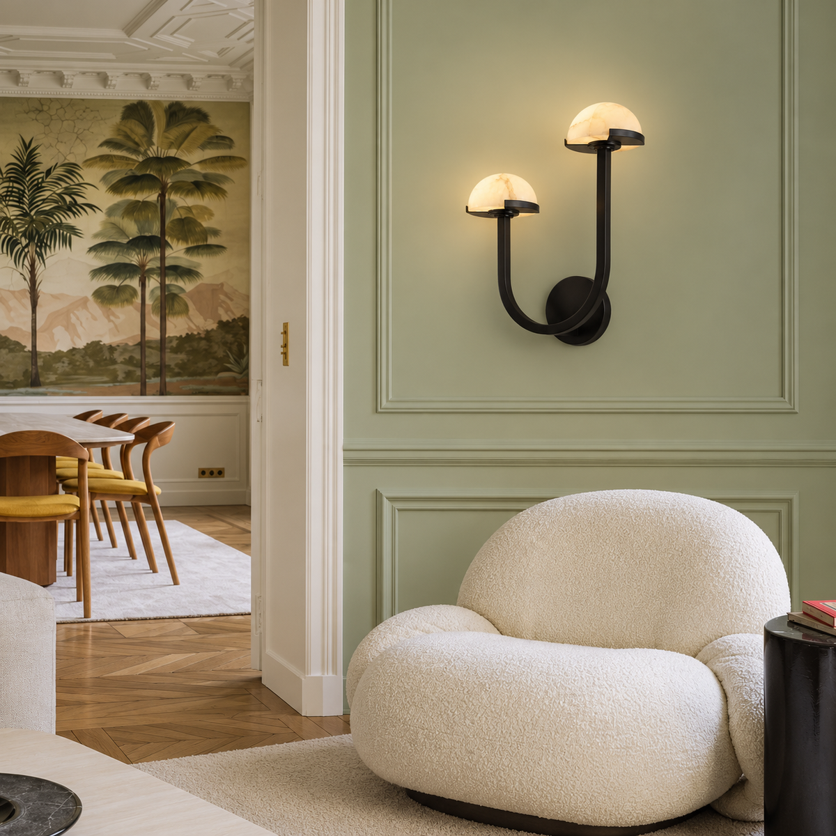 Double alabaster wall sconce installed on a sage wall beside a cream armchair.