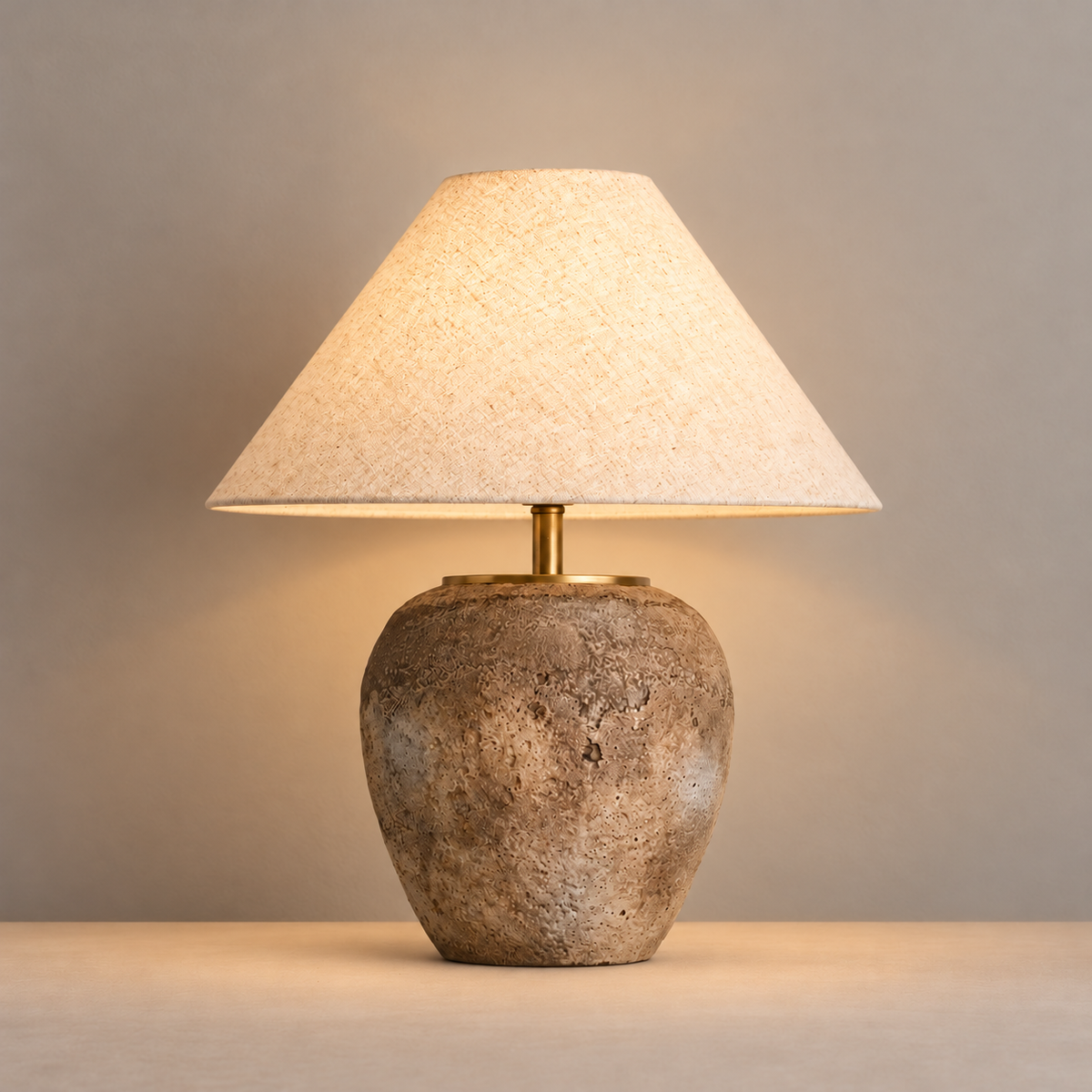 Taupe ceramic table lamp with its textured shade illuminated.