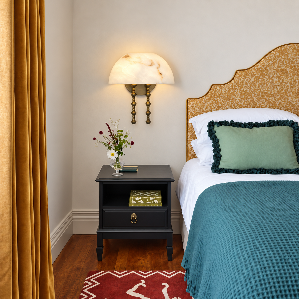 Dome alabaster wall sconce beside teal bedding and golden curtains.