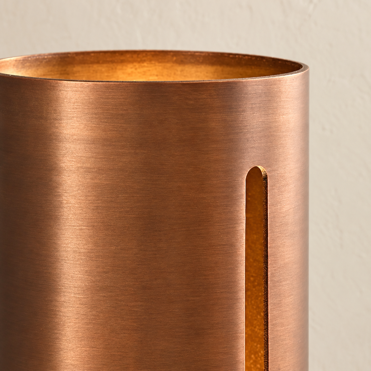 Close-up of the copper wall light’s open rim, patinated surface and narrow slit.
