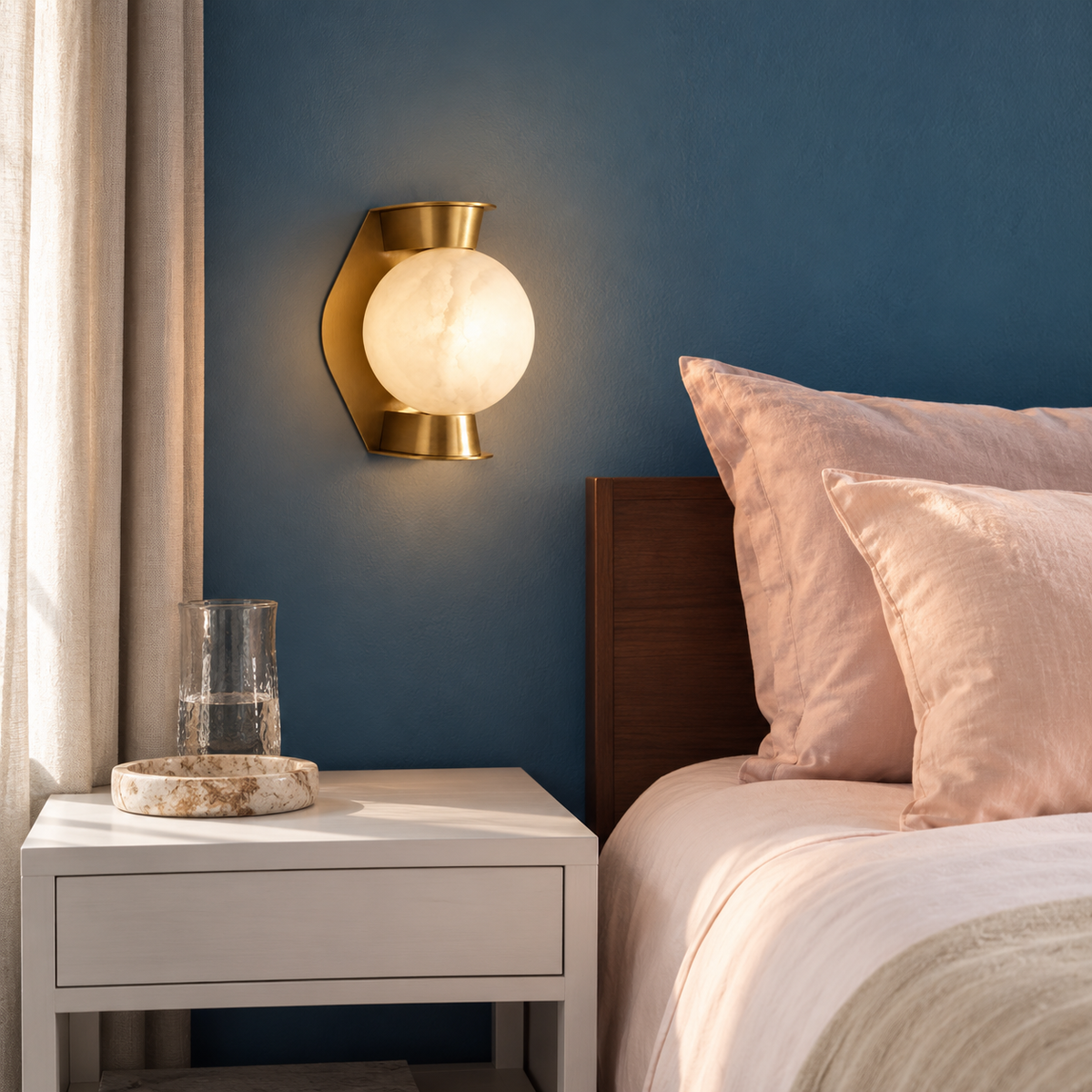 Alabaster globe and brass wall sconce, mounted beside a bed