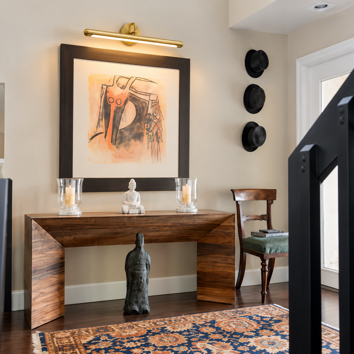 Brass picture light installed above framed art in an entryway.
