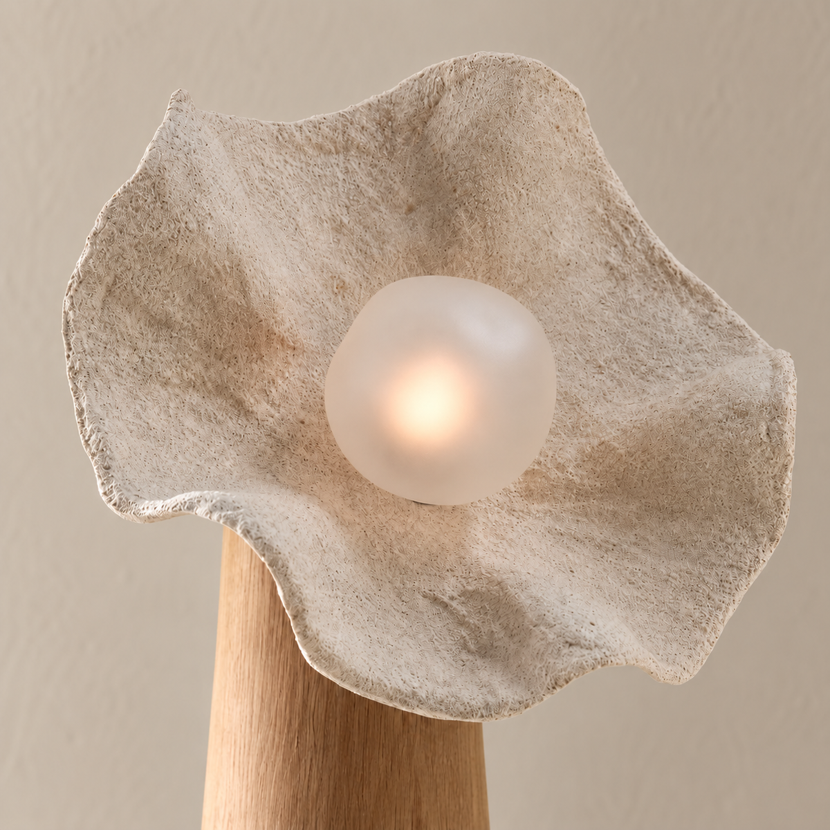 Close view of the Petal lamp's plaster-look resin texture and softly illuminated centre.