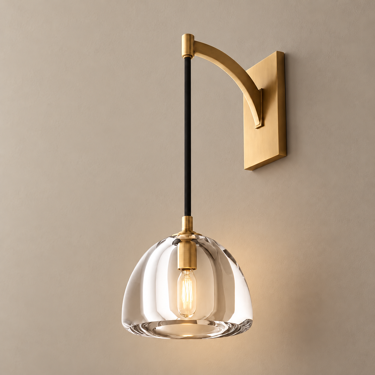 Clear glass dome and metal arm wall sconce, illuminated on a stone-beige wall