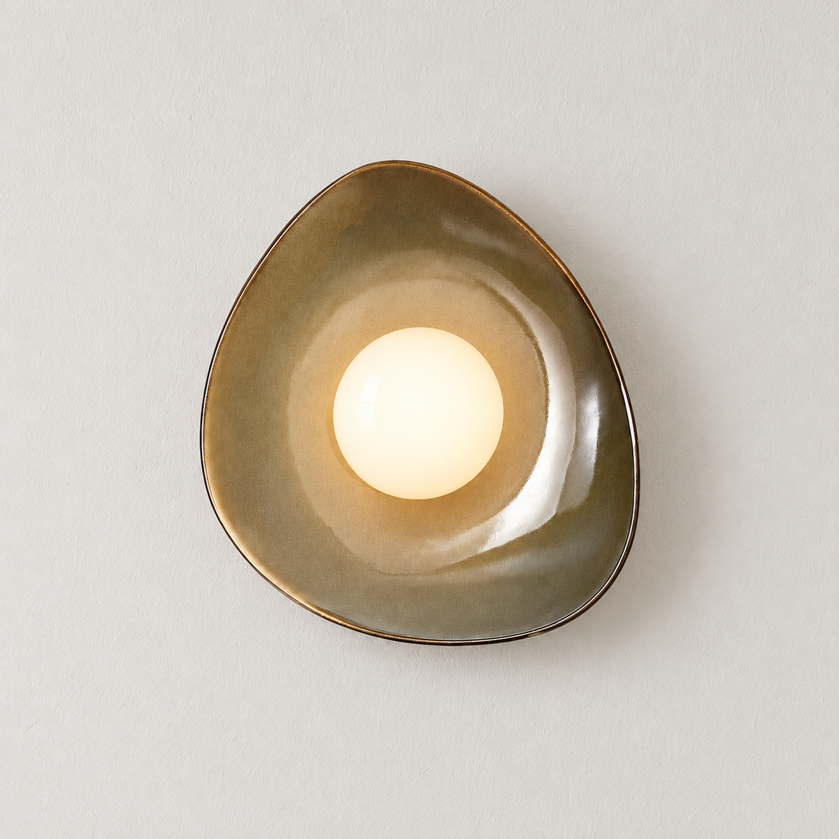 The same ceramic wall sconce with its opal globe illuminated.