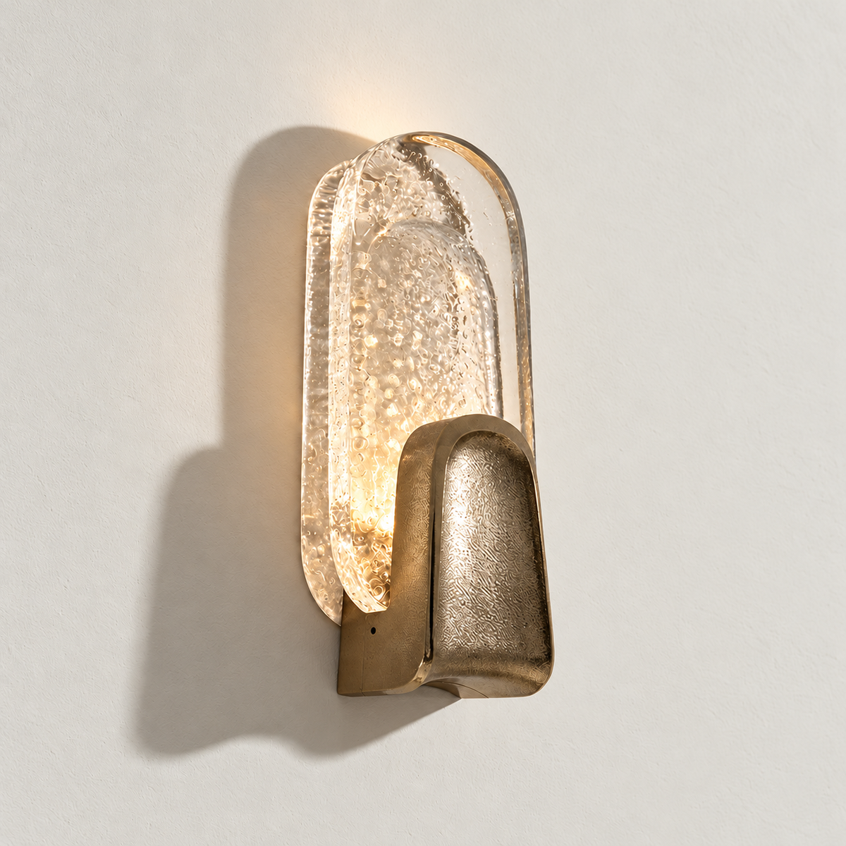 Brass bubbled glass wall sconce illuminated on warm ivory.