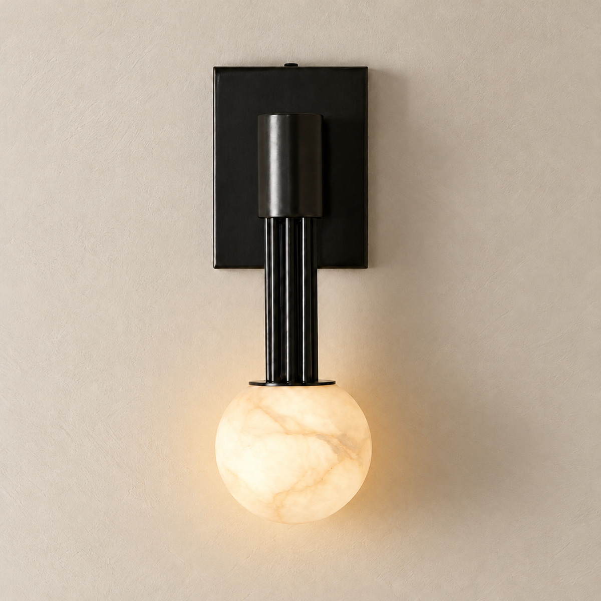 Black alabaster globe wall sconce illuminated on warm ivory.
