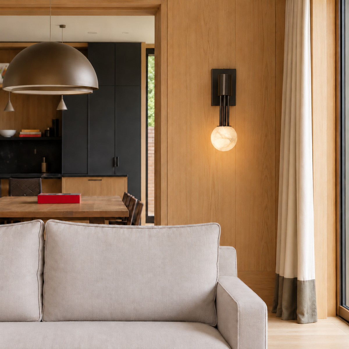 Black and alabaster globe wall sconce on timber paneling above a gray sofa.