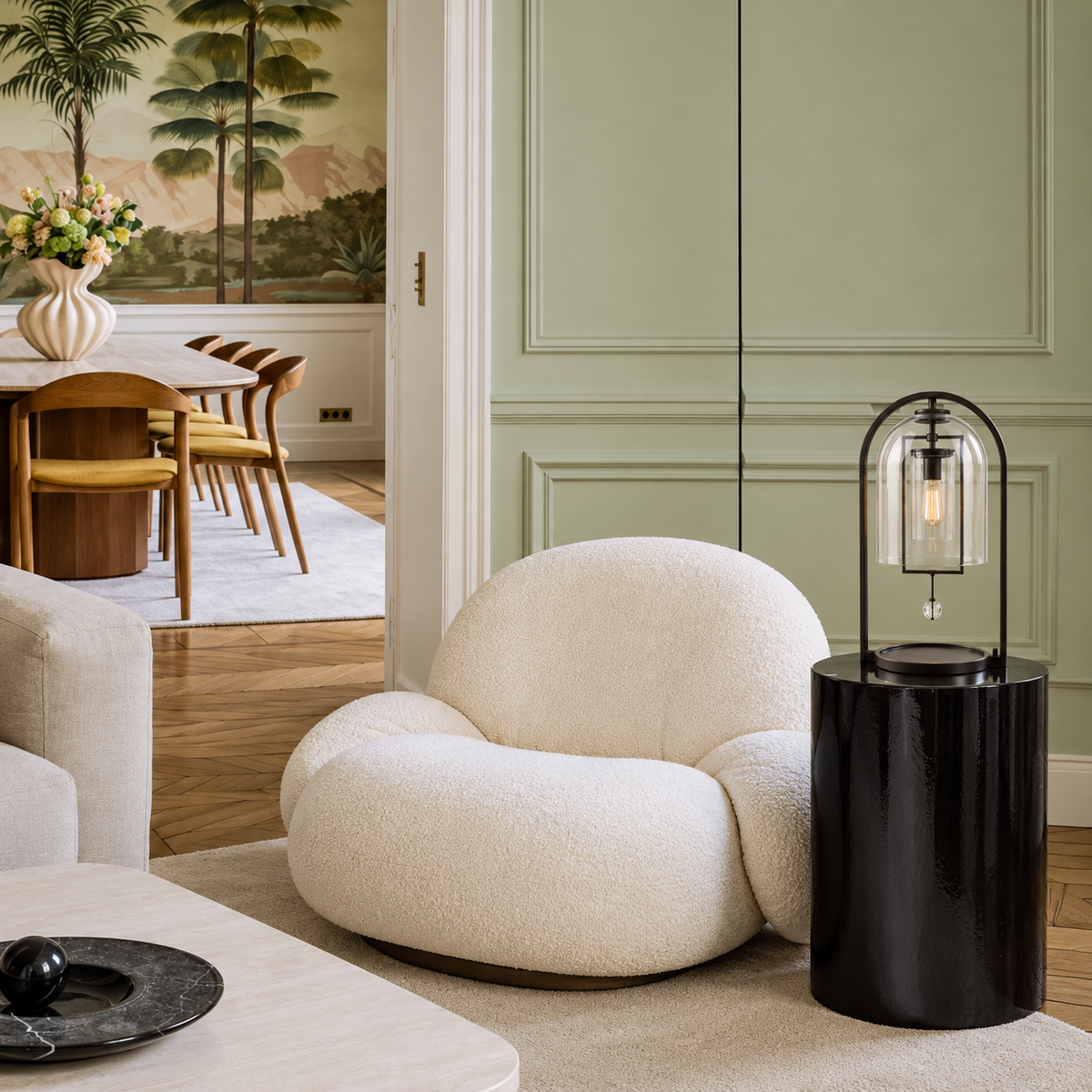 Black glass dome table lamp beside a cream chair in a sage living room