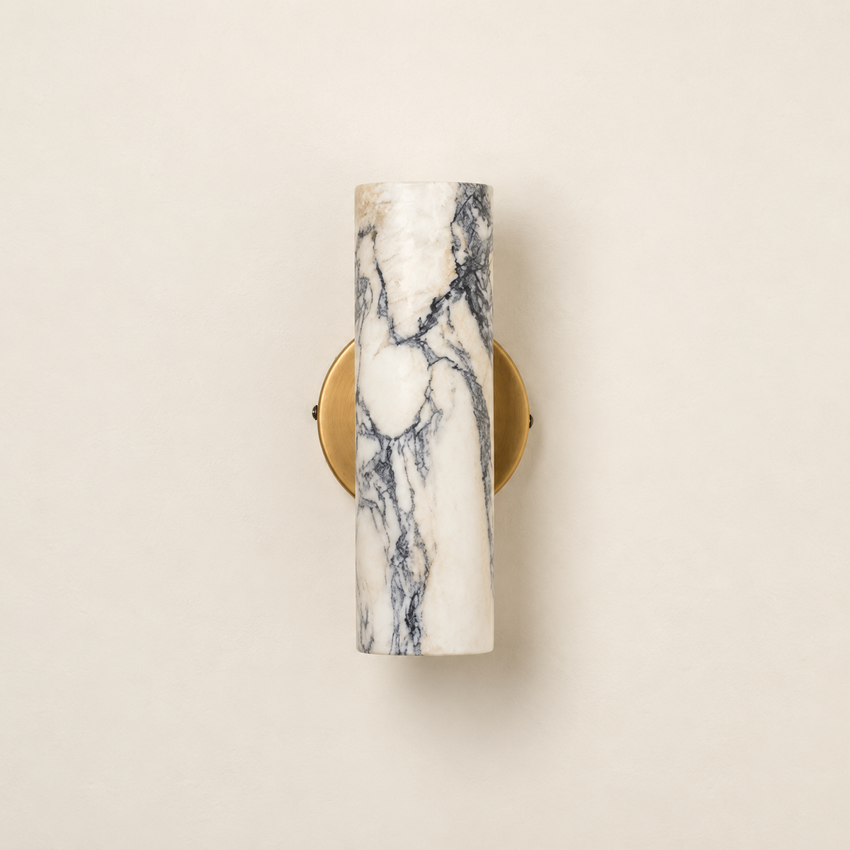 Front view of the unlit veined marble cylinder and round brass backplate on a beige wall.