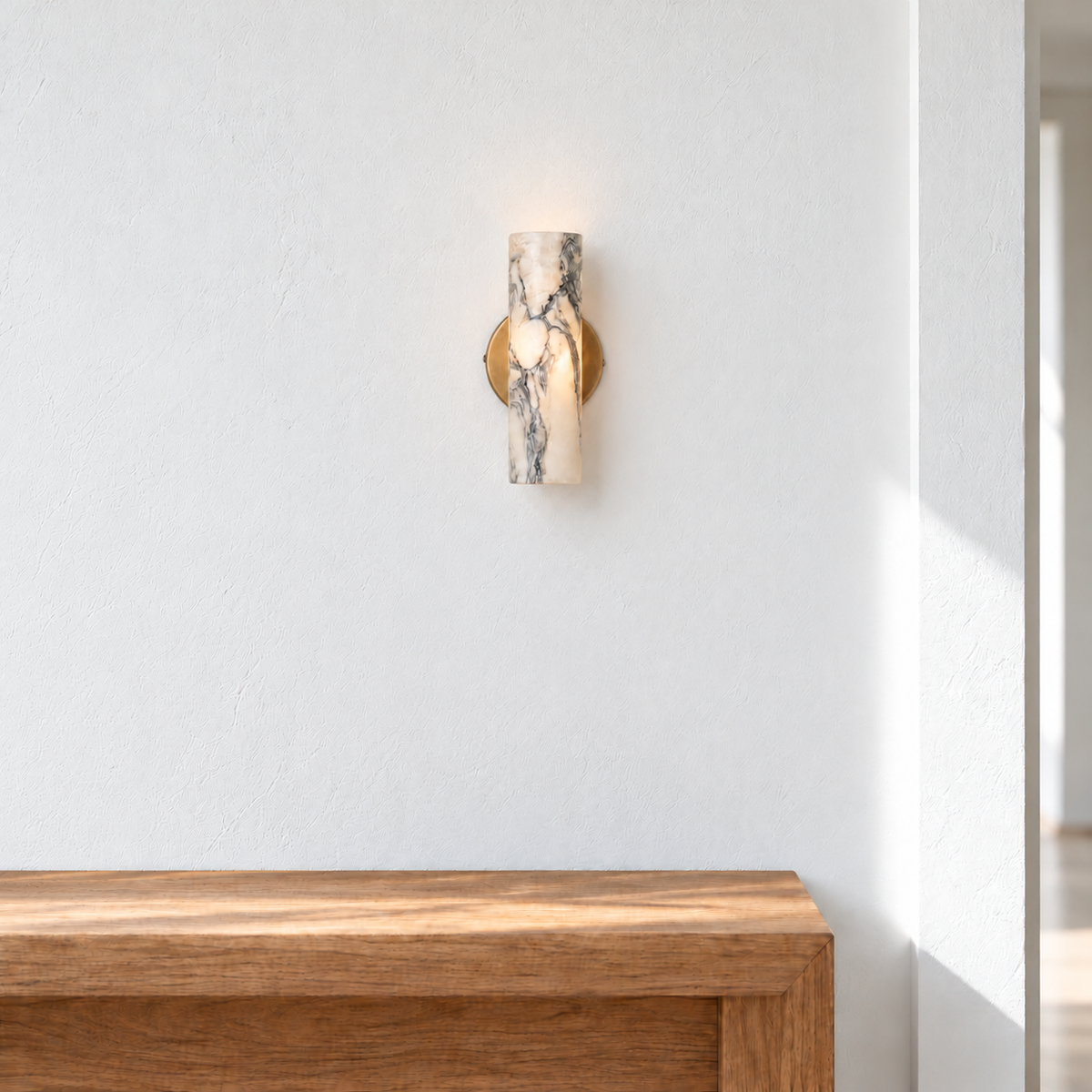 Veined marble cylinder wall sconce with a brass backplate above a clear oak entryway console.