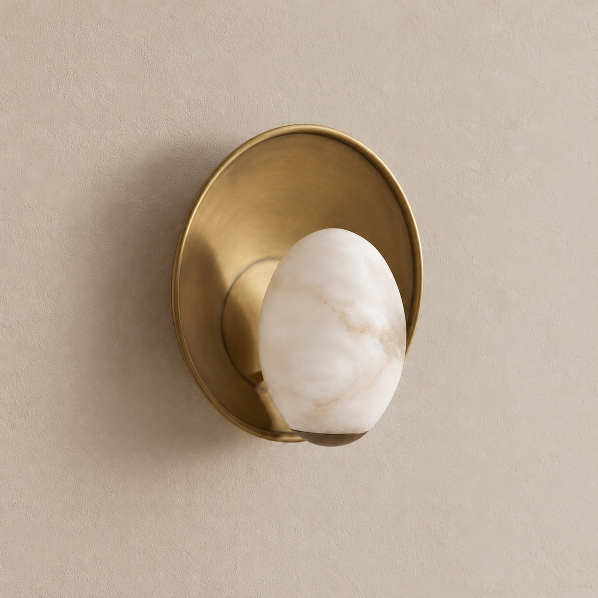 Angled view of the alabaster egg sconce showing its projecting shade, brass support and rounded backplate.