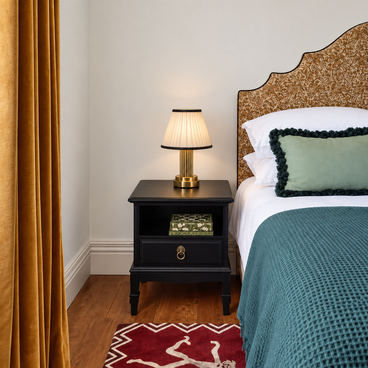 Small brass table lamp on a bedside table beside teal bedding