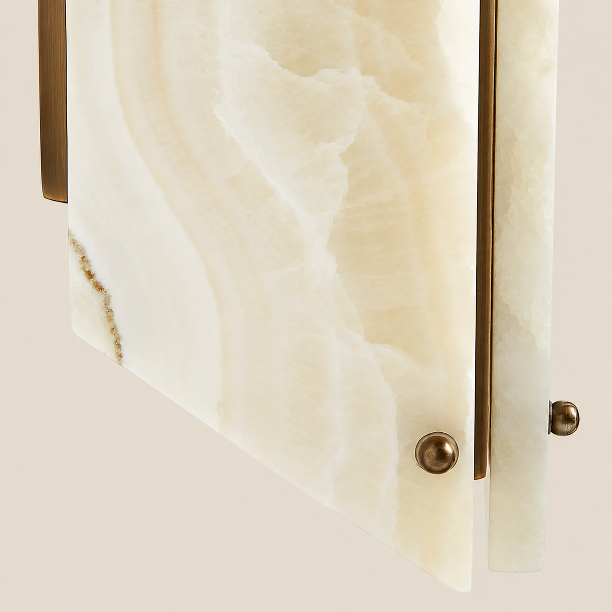 Close-up of onyx veining, brass trim and round fasteners.