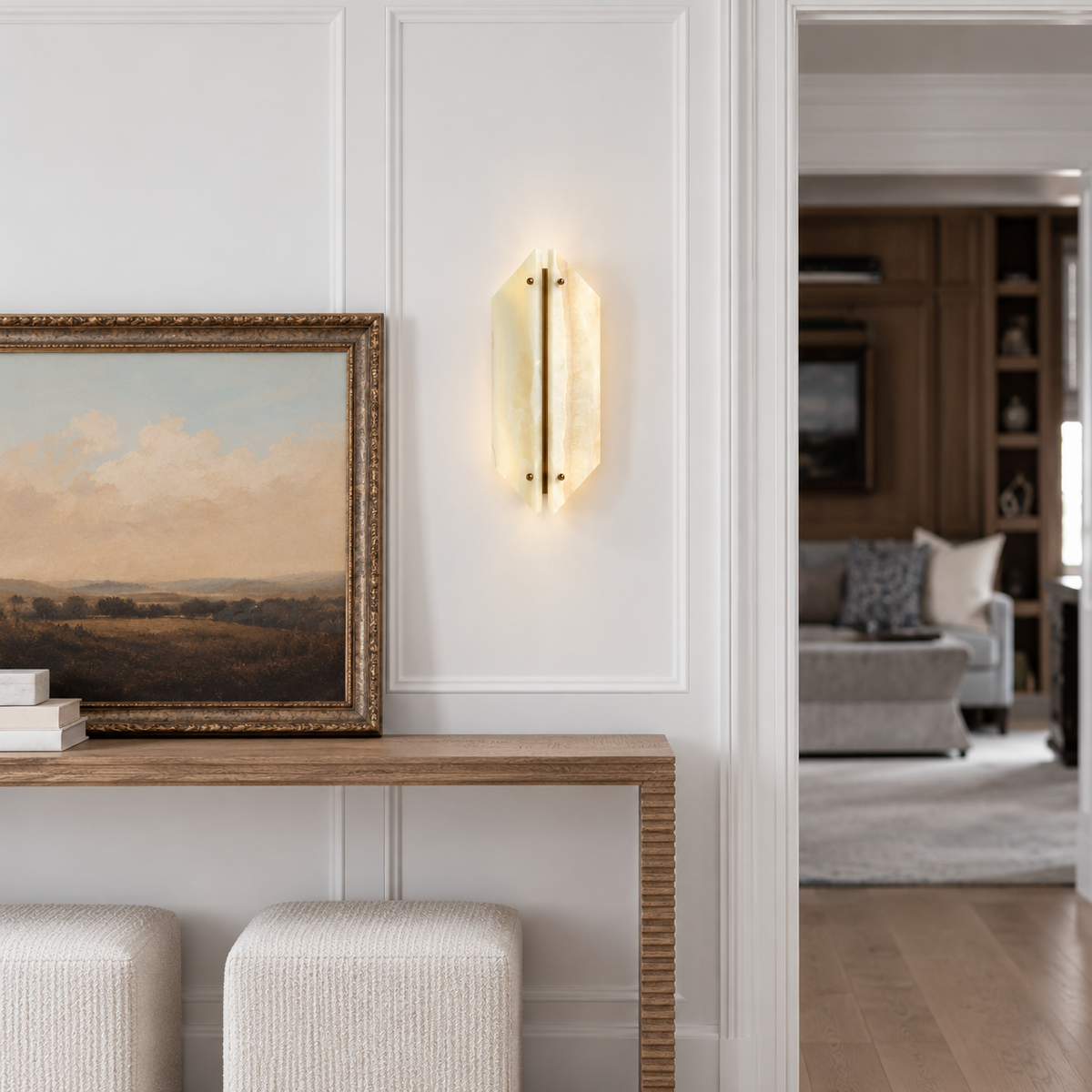 Onyx and brass sconce installed above an entryway console beside framed artwork.
